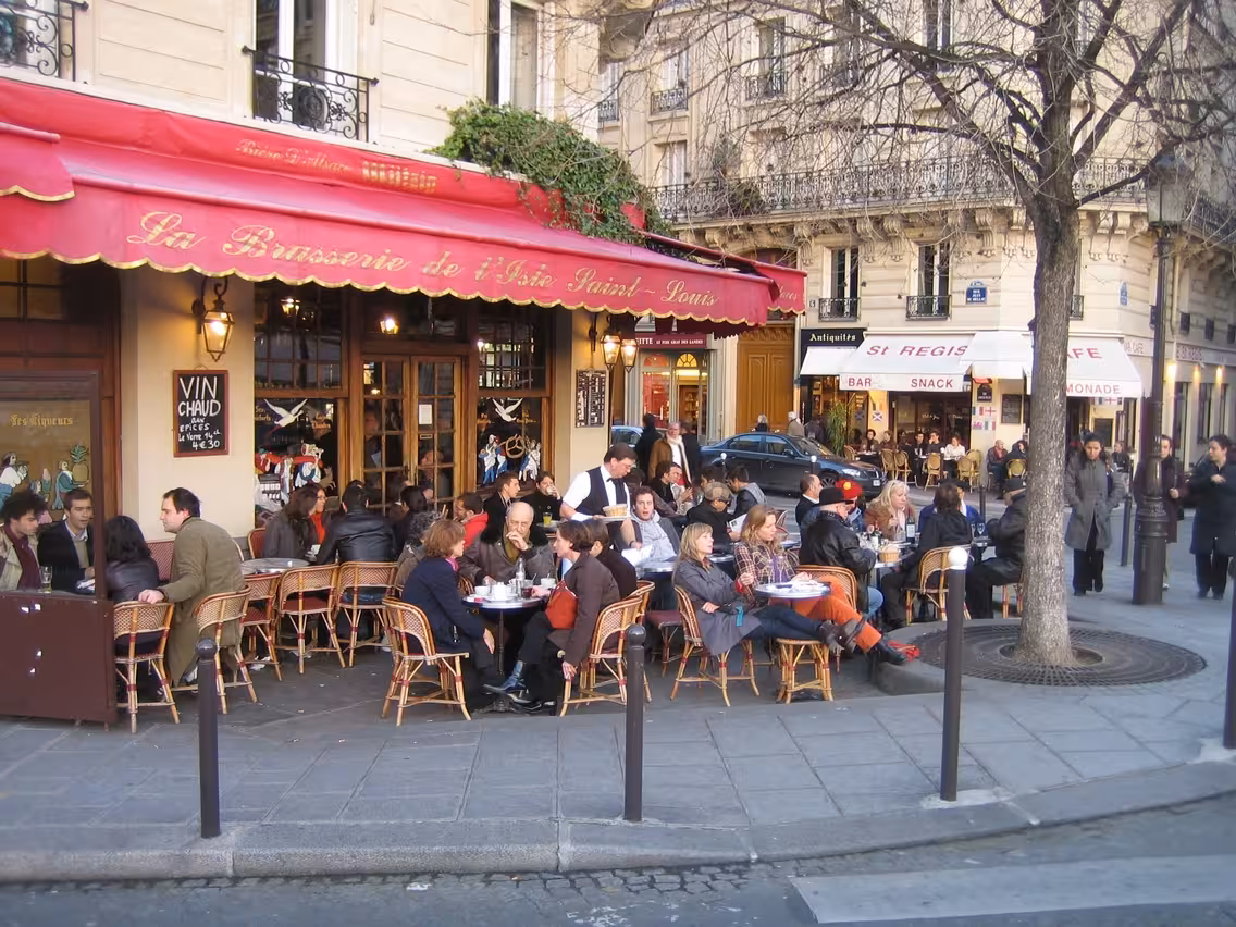 People enjoying outdoor dining at a bustling Parisian café, capturing the essence of Montmartre's vibrant atmosphere.