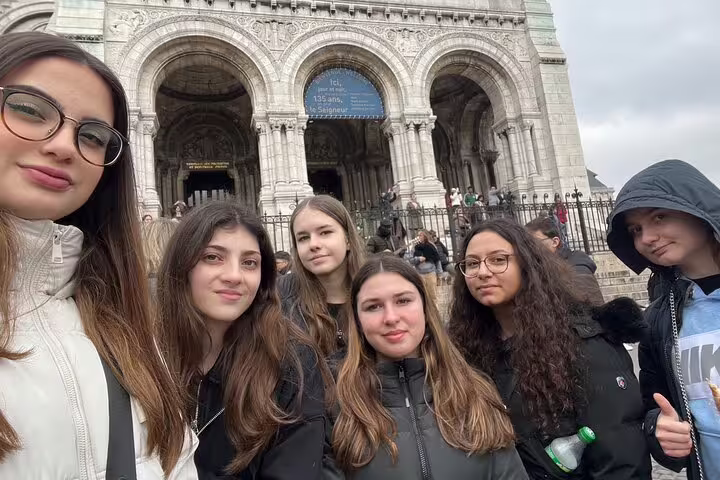 Group selfie on Sacré-Cœur steps in Montmartre, Paris, enjoying a self-guided scavenger hunt and sights tour