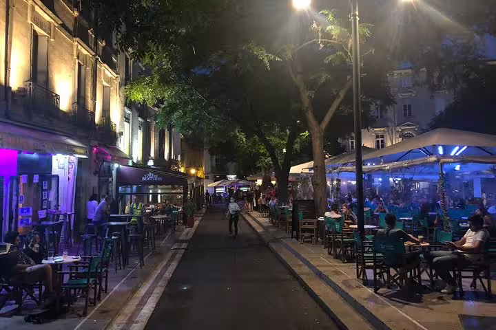 Nighttime street in Montpellier with lively terraces and lights, ideal stop on a self-guided e-scavenger hunt route