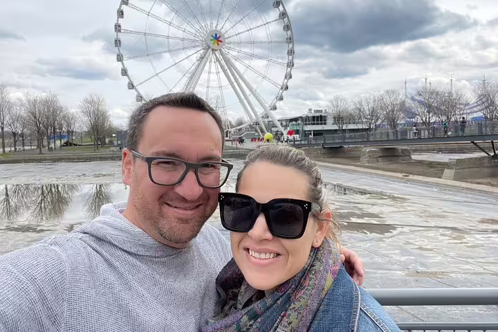 Couple selfie by Old Port Ferris wheel on Montréal scavenger hunt and city highlights walking tour route