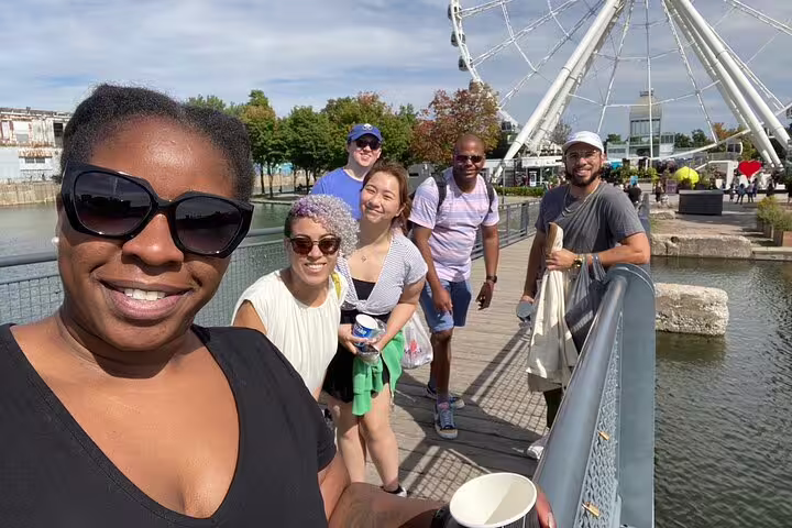 Friends on a waterfront boardwalk near La Grande Roue in Montreal during a scavenger hunt and highlights walk