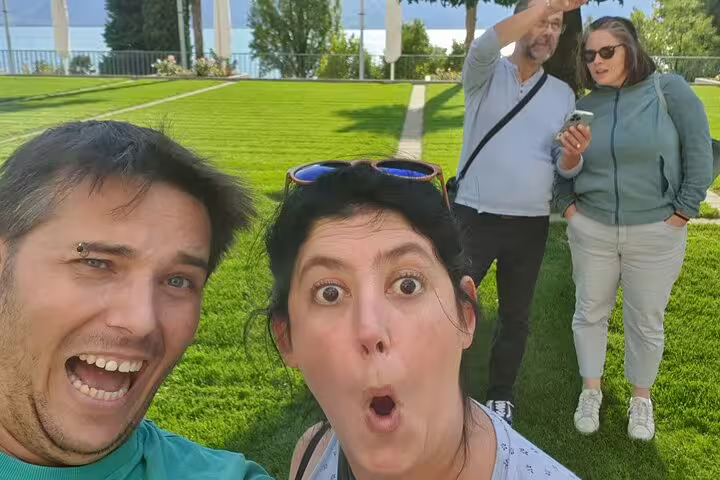 Friends enjoying a Montreux self-guided scavenger hunt tour in a lakeside park, checking clues on phone