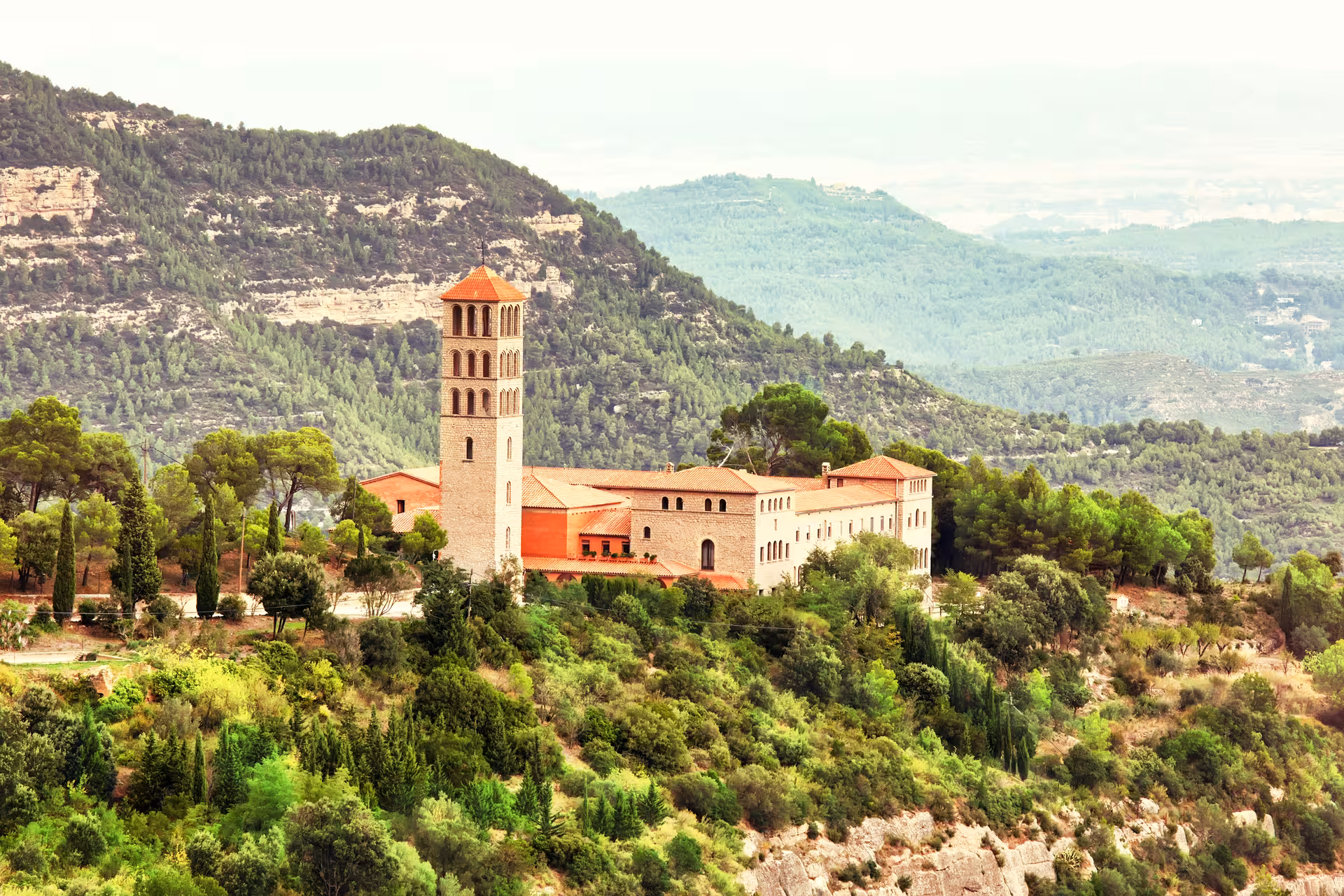Montserrat Monastery with bell tower and red roofs amid Catalan hills, half-day private tour from Barcelona