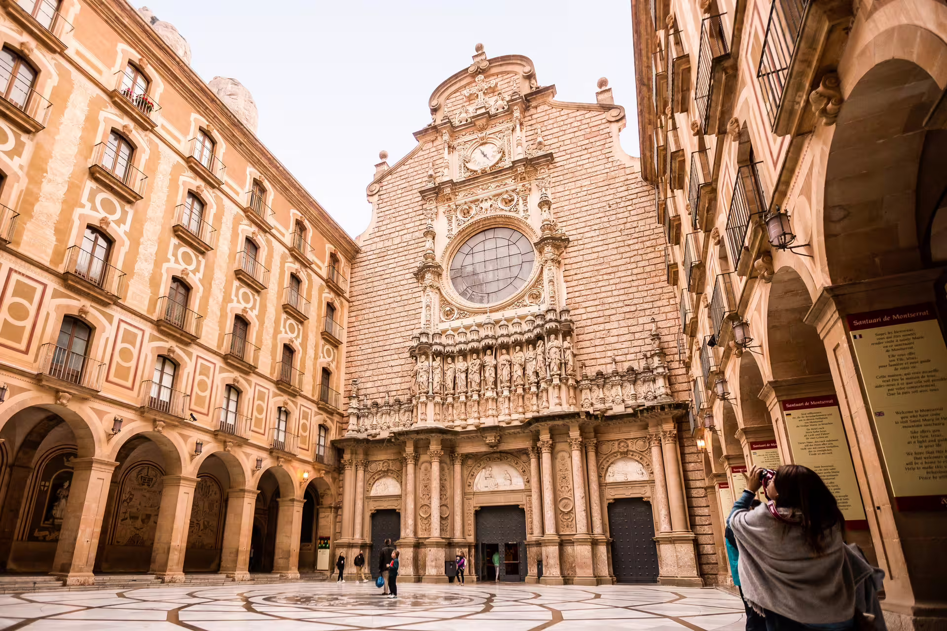 Tourists admire the ornate facade of Montserrat Monastery, a highlight of the Extended Montserrat, Tapas & Wine tour with cogwheel train.