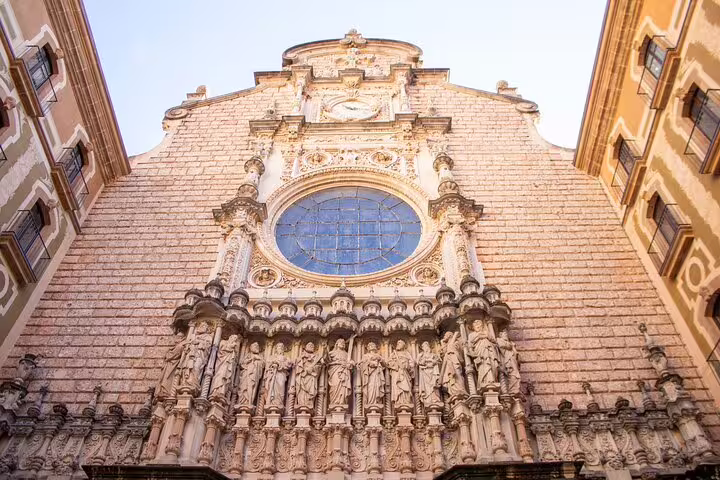 Ornate façade of Montserrat Monastery showcasing intricate carvings and a large stained glass window.