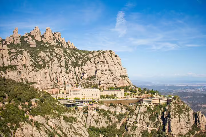 Aerial view of Montserrat mountain and monastery under clear blue skies, highlighting the stunning natural landscape.