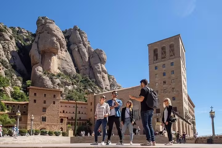 Tourists exploring the historic Montserrat Monastery with stunning mountain backdrop on the Montserrat + Penedés Wine Tour.