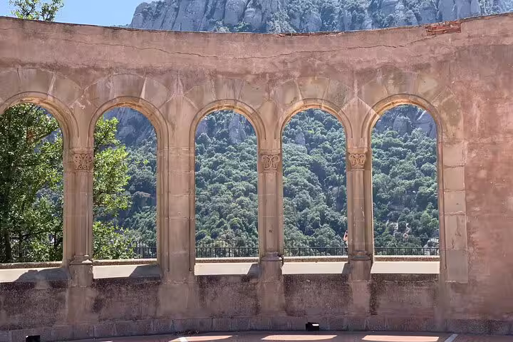 Marvel at Montserrat's majestic mountains through ancient arches on an exclusive half-day tour with hotel pick-up.