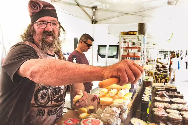 Local vendor offering cheese at a vibrant market, part of the Montserrat Private Tour with lunch and Penedes wine tasting.