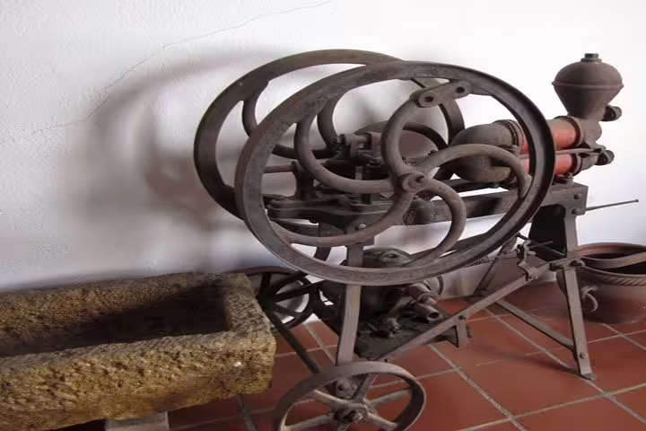 Vintage wine press machine displayed in Penedés wine cellar, showcasing traditional winemaking on Montserrat + Wine Cellar Tour.
