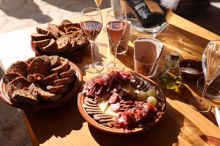Delight in a Montserrat private tour with a Penedes winery lunch featuring charcuterie, fresh bread, and sparkling wine tasting.