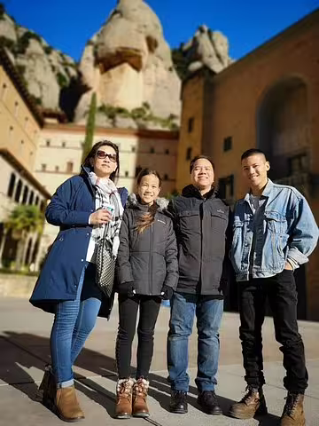 Group enjoying Montserrat tour with scenic mountain backdrop, highlighting family-friendly travel and wine tasting in Penedes.