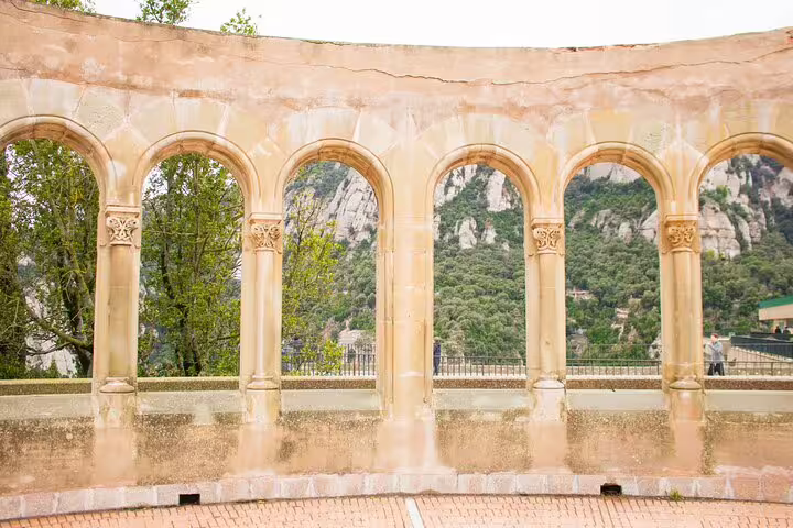 Historic stone arches framing lush greenery and mountainous vistas at Montserrat, enhancing the tour experience.