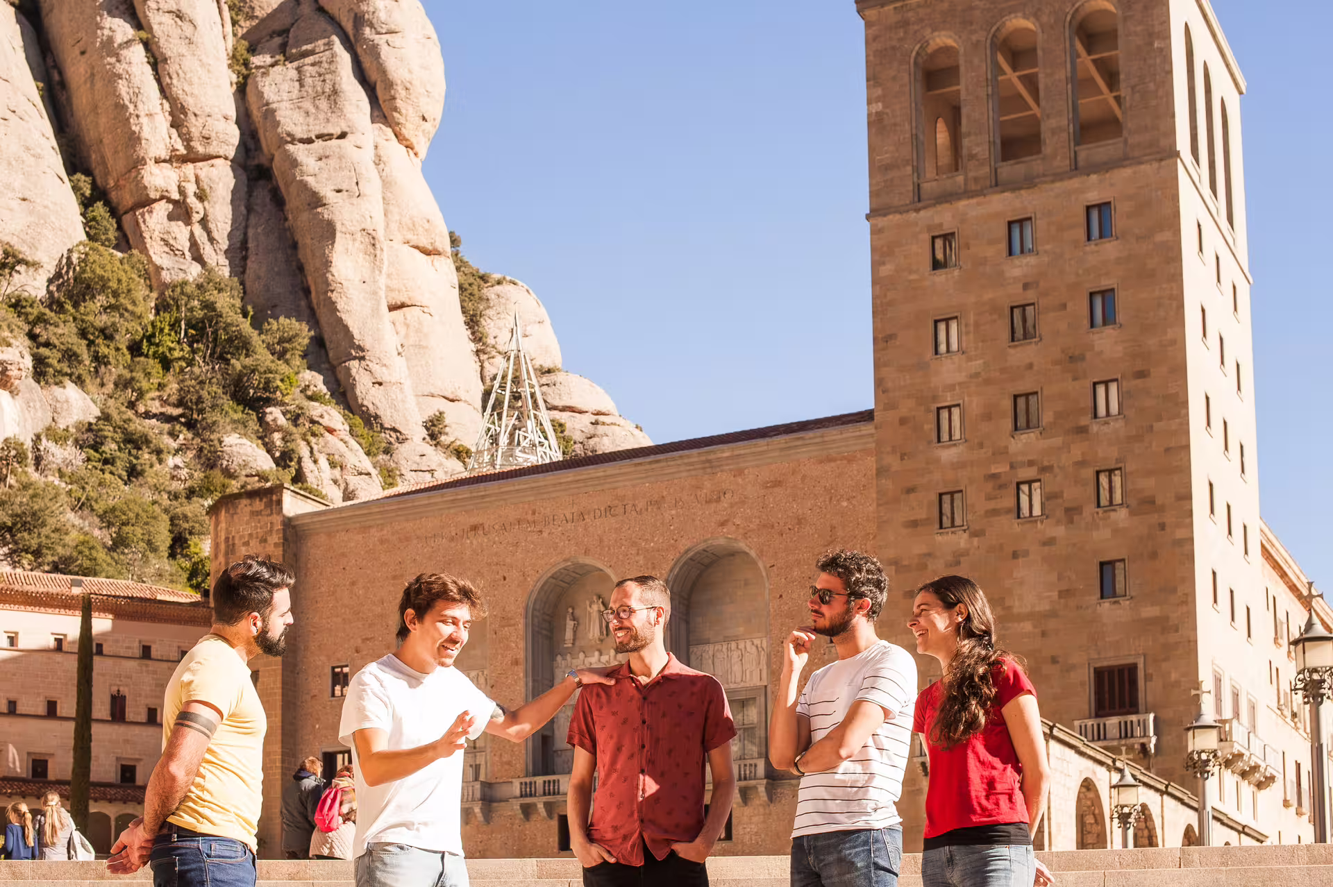 Group enjoying a sunny day at Montserrat with historic architecture, perfect for tapas and wine tour with cogwheel train adventure.
