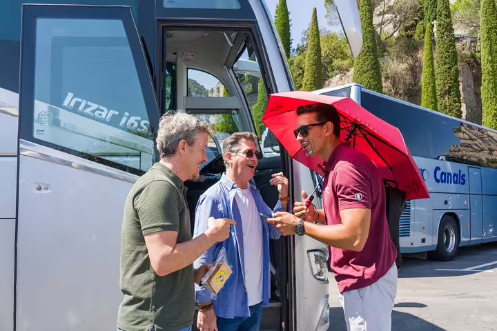 Tourists chatting happily by a tour bus, ready to explore Montserrat with a guide.