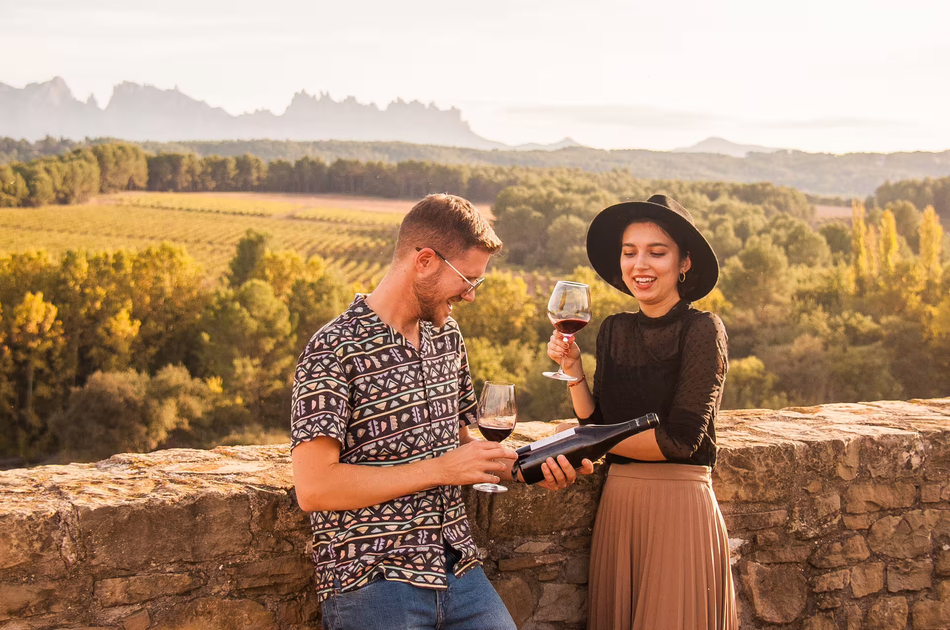 Couple enjoying wine with Montserrat mountain views during late-start tour, featuring food, wine, and cogwheel train adventure.