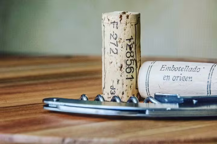 Close-up of a wine cork and corkscrew on wood, emphasizing the artisanal craft of Montserrat's organic wineries.
