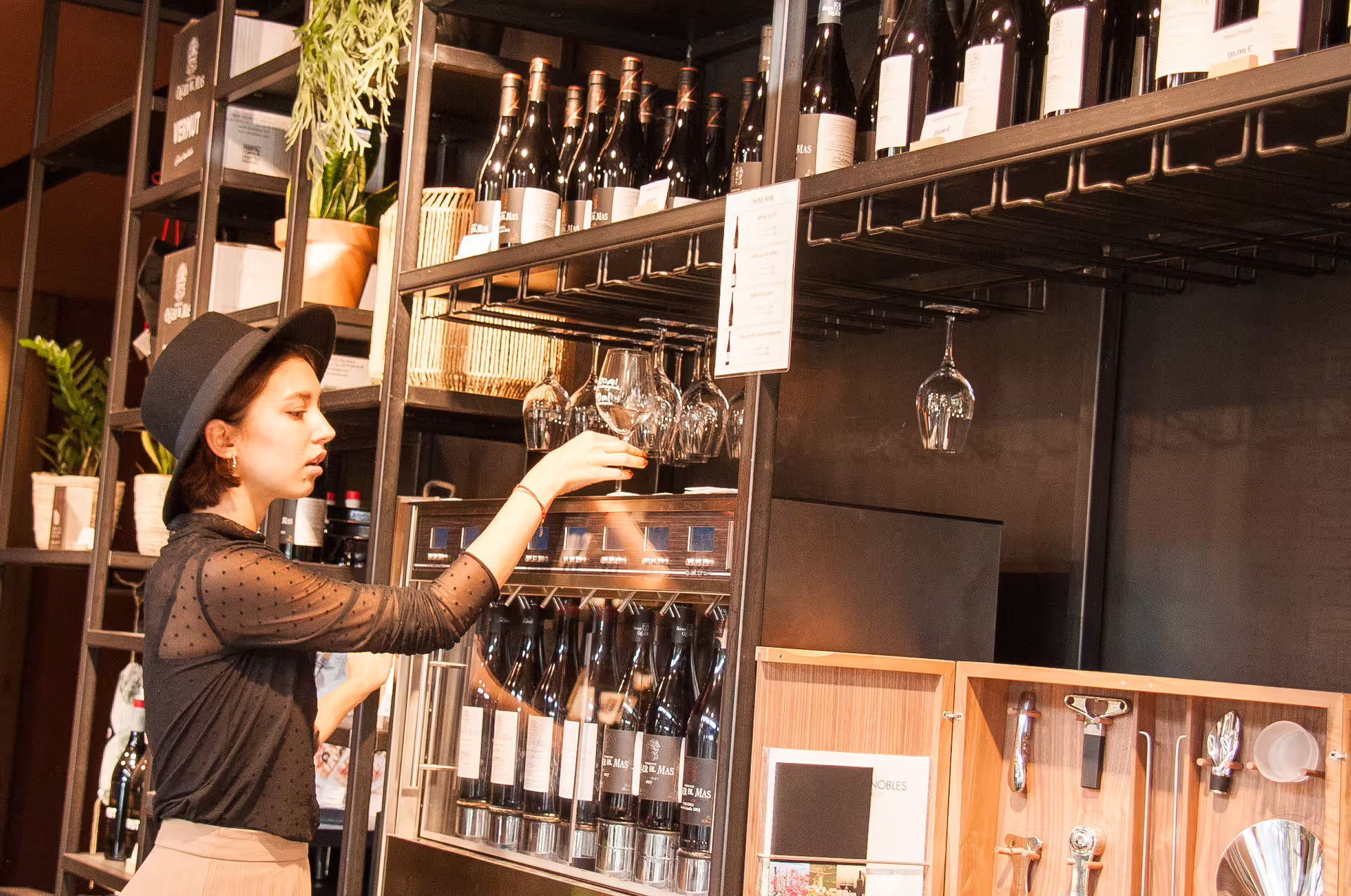 Woman selecting wine glasses in a stylish Montserrat wine shop, highlighting local wine experiences.