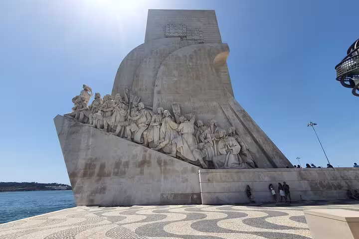 Monument of Discoveries in Belem, Lisbon, under bright blue skies, showcasing historic explorers, part of a full-day small-group tour.