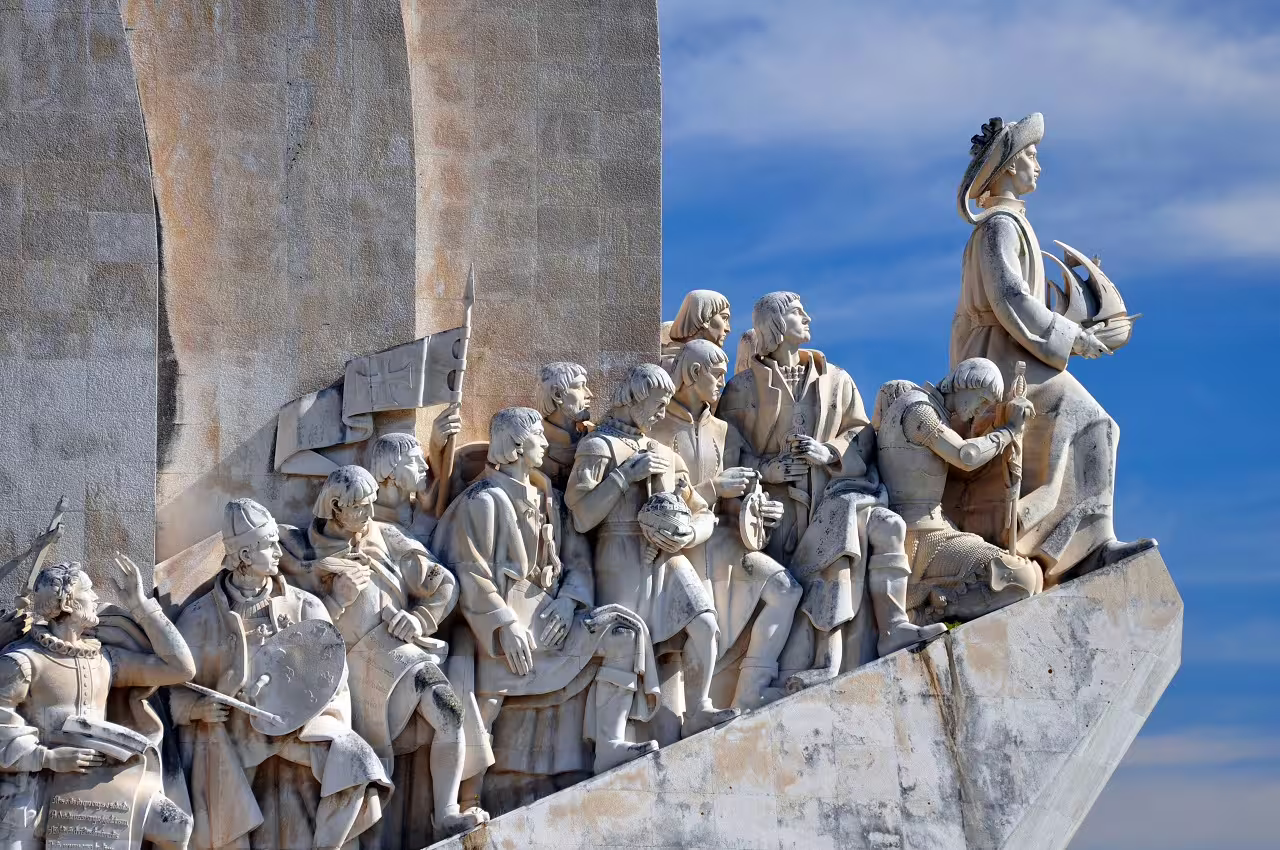 Monument of Discoveries in Lisbon, Portugal, featuring detailed sculptures of explorers against a clear blue sky.