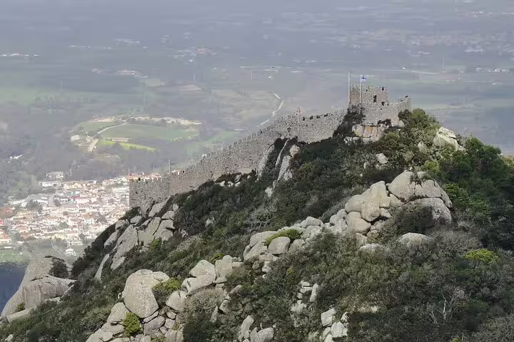 A breathtaking view of the ancient Moorish Castle in Sintra, Portugal, surrounded by lush greenery and rocky landscape.