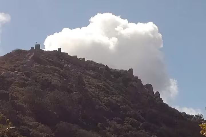 Moorish Castle atop a lush hill under a bright sky in Sintra, Portugal, seen on a private tour from Lisbon or Cascais.