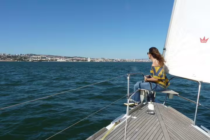 Passenger enjoying a serene morning sailing tour on the Tagus River with Lisbon's skyline in the background.