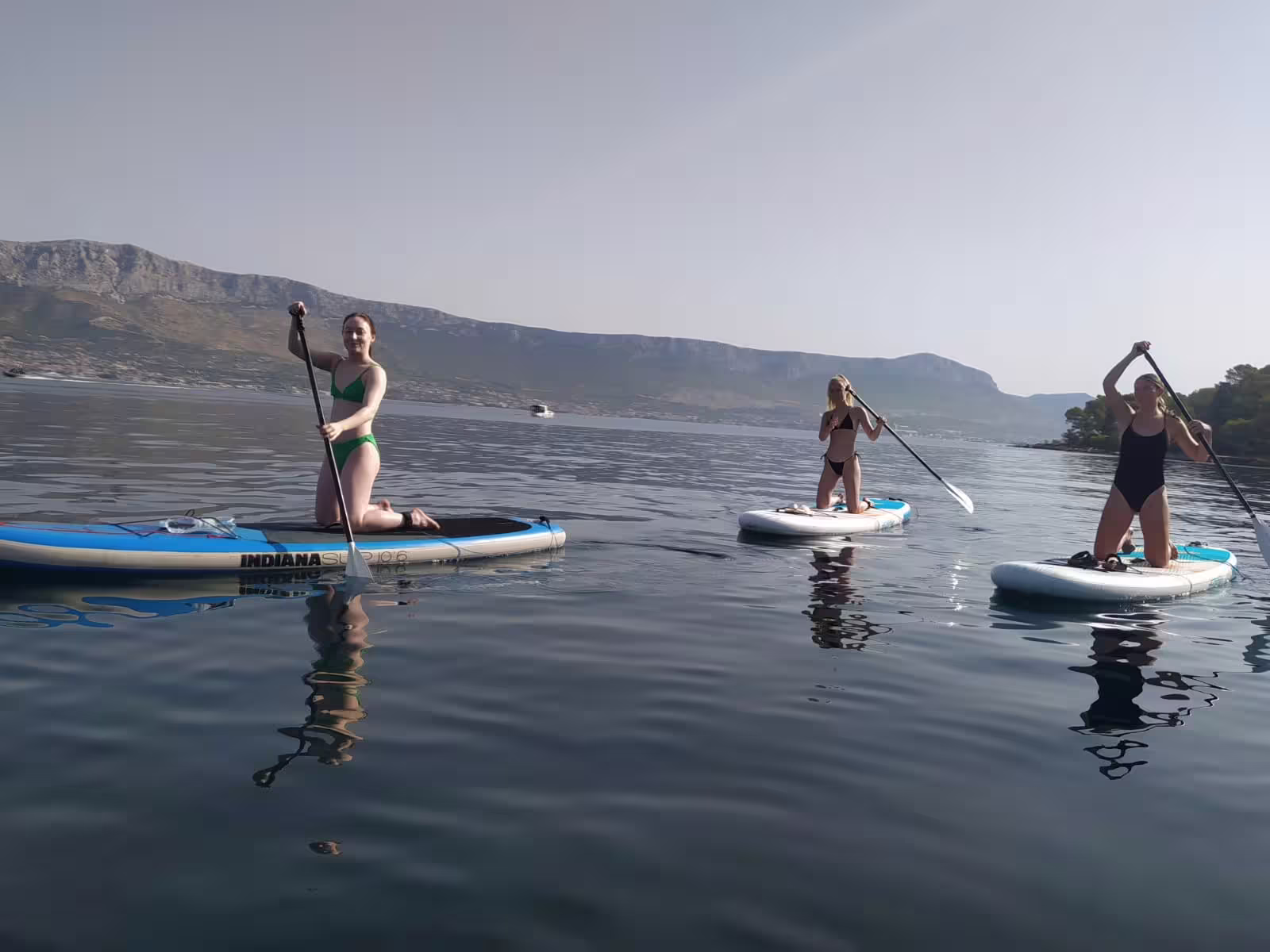 Group paddling on calm Adriatic waters during a morning stand up paddle tour in Split with mountain views
