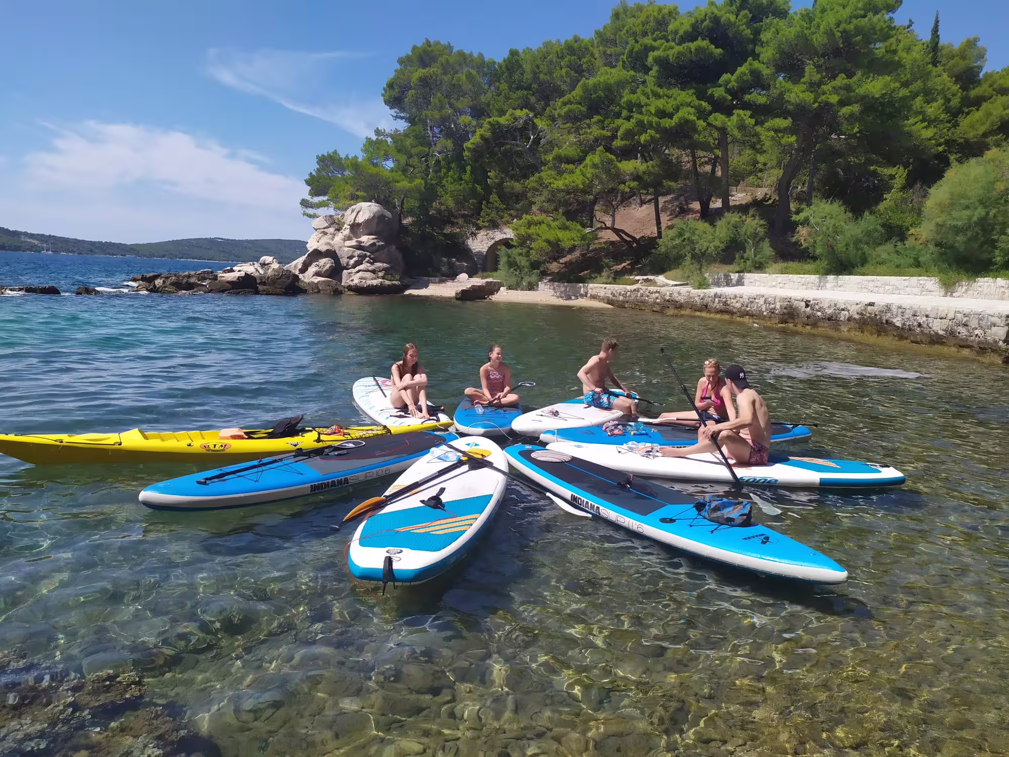 Group resting on SUP boards in a clear Split bay, ideal for a morning stand up paddle tour in Croatia