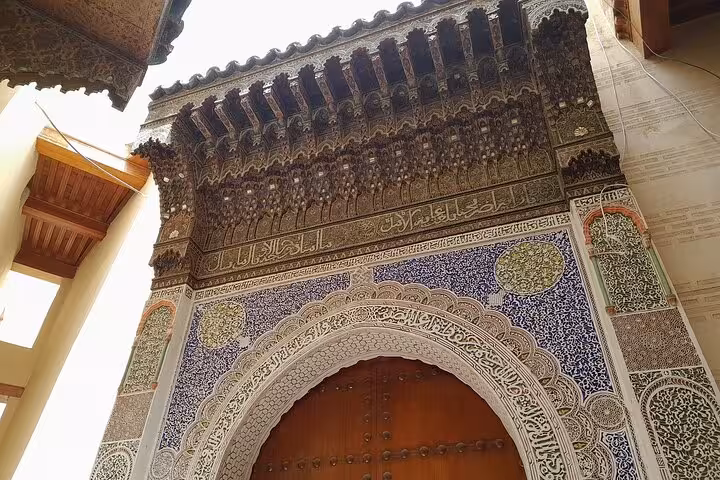 Intricate Moroccan archway with detailed carvings and vibrant mosaic tiles in Fez's Old Medina.