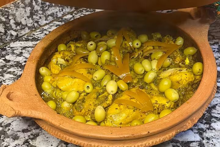 Delicious Moroccan chicken tagine with olives and preserved lemons in a clay pot prepared during a cooking class.