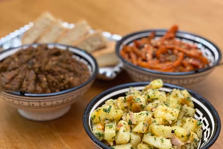 Traditional Moroccan dishes with spiced potatoes, carrot salad, and minced meat stew in decorative bowls.