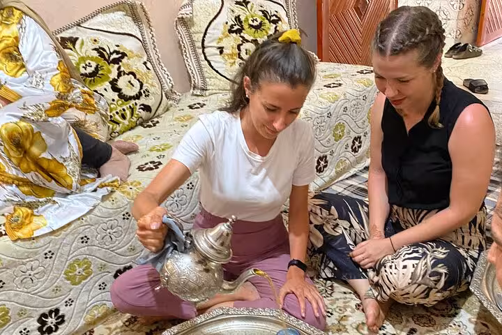 Two women enjoying a Moroccan tea ceremony during a cooking class with traditional decor around them.