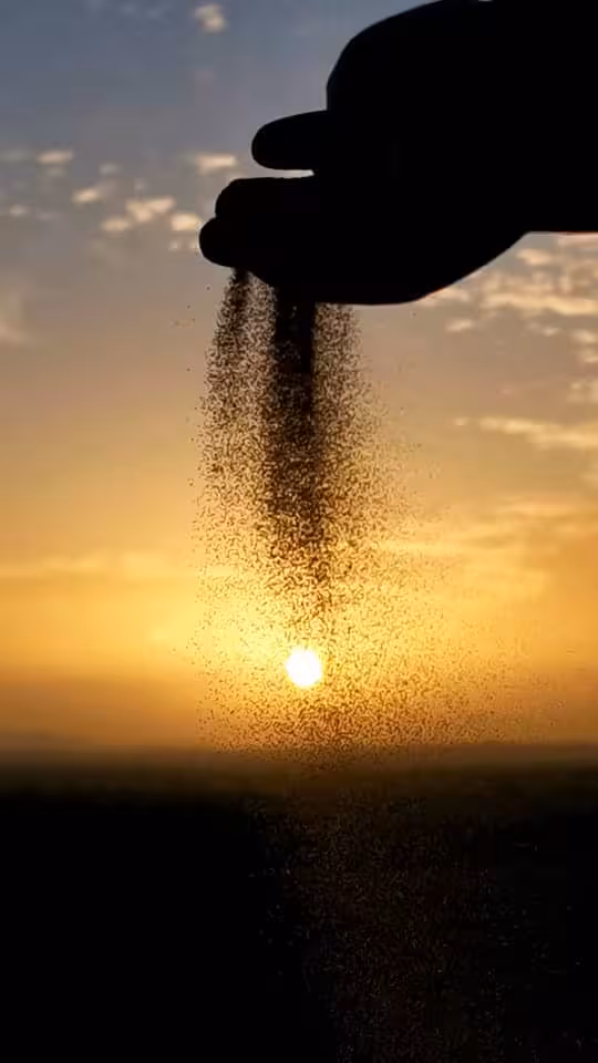 Hand letting desert sand fall at sunset in Morocco, Sahara dunes experience on Best of Morocco tour