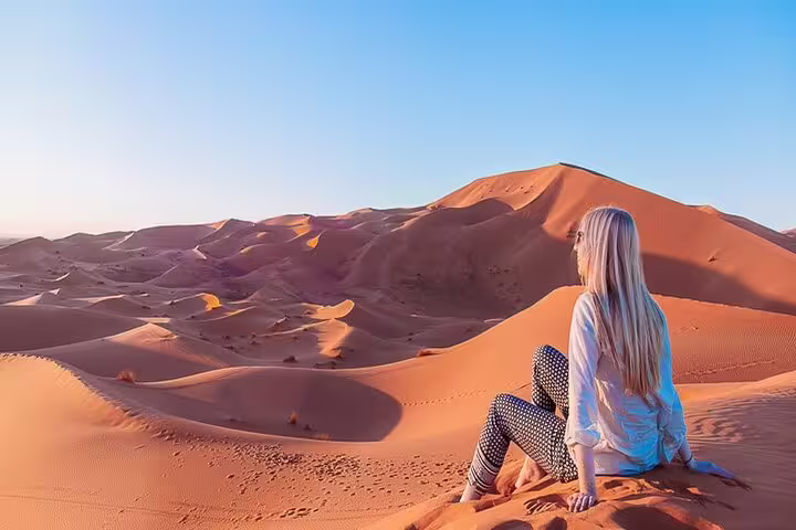 Traveler overlooking Erg Chebbi sand dunes at sunset, Sahara desert highlight on 12-day Morocco tour from Casablanca