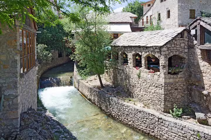 Stone riverside houses and a narrow canal in Mostar Old Town on a day trip from Makarska Riviera