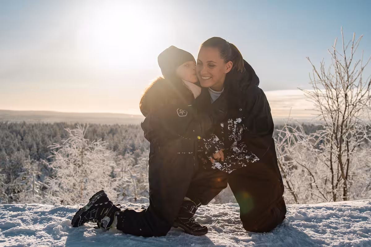 Mother and child share a joyful moment in snowy Rovaniemi landscape during a private holiday photo session.