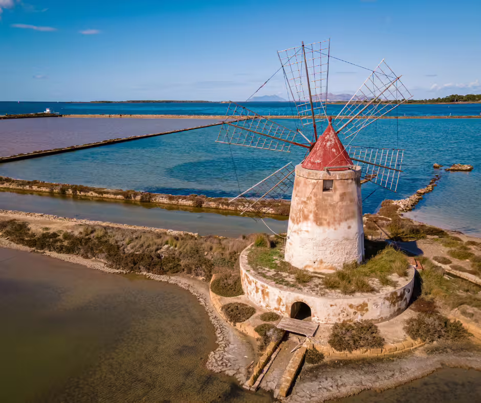 Old stone windmill rising above the shimmering salt flats of Mothia Island in Lo Stagnone lagoon on a private tour from Palermo