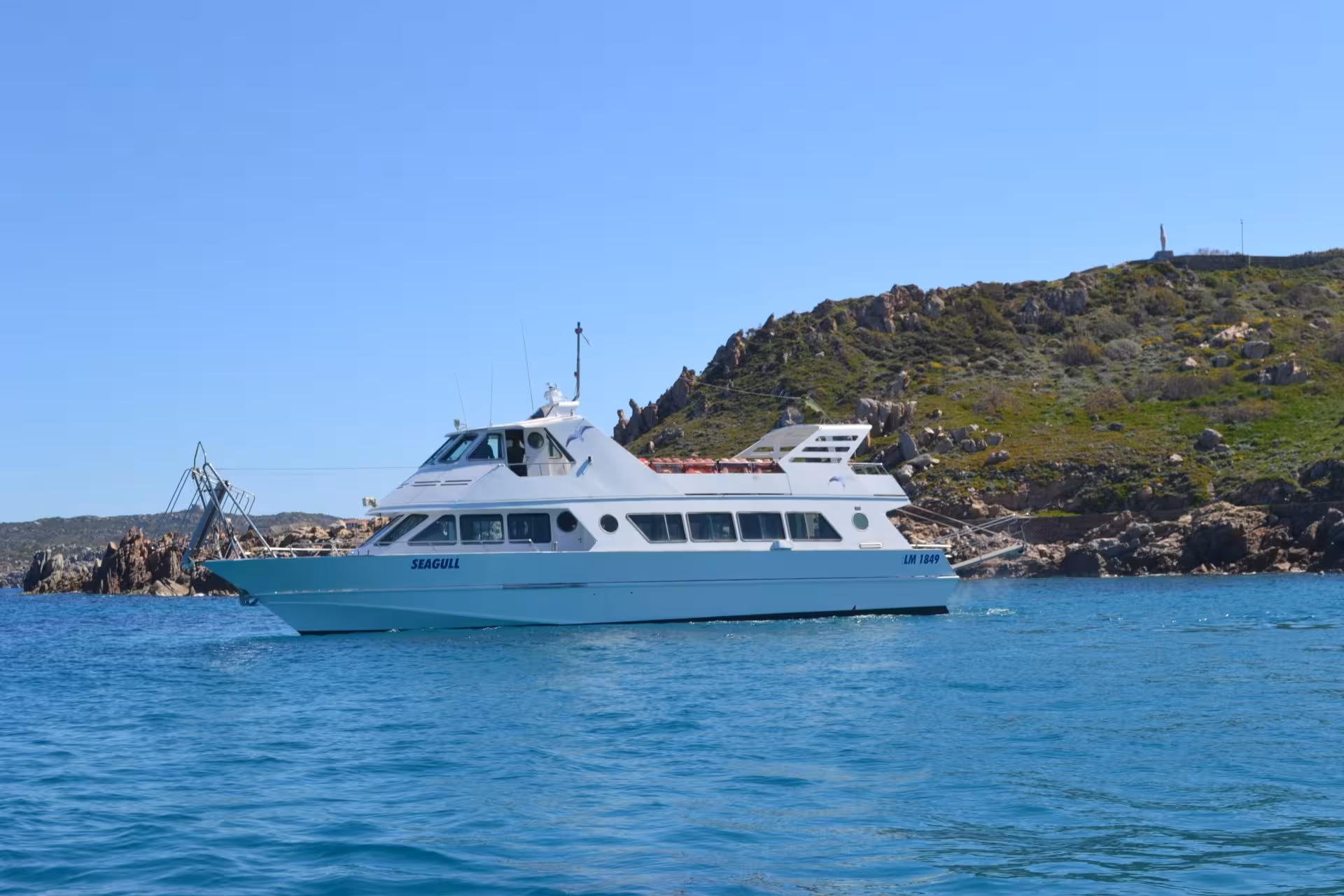Motorboat cruising through the blue waters of the La Maddalena Archipelago, offering stunning coastal views.