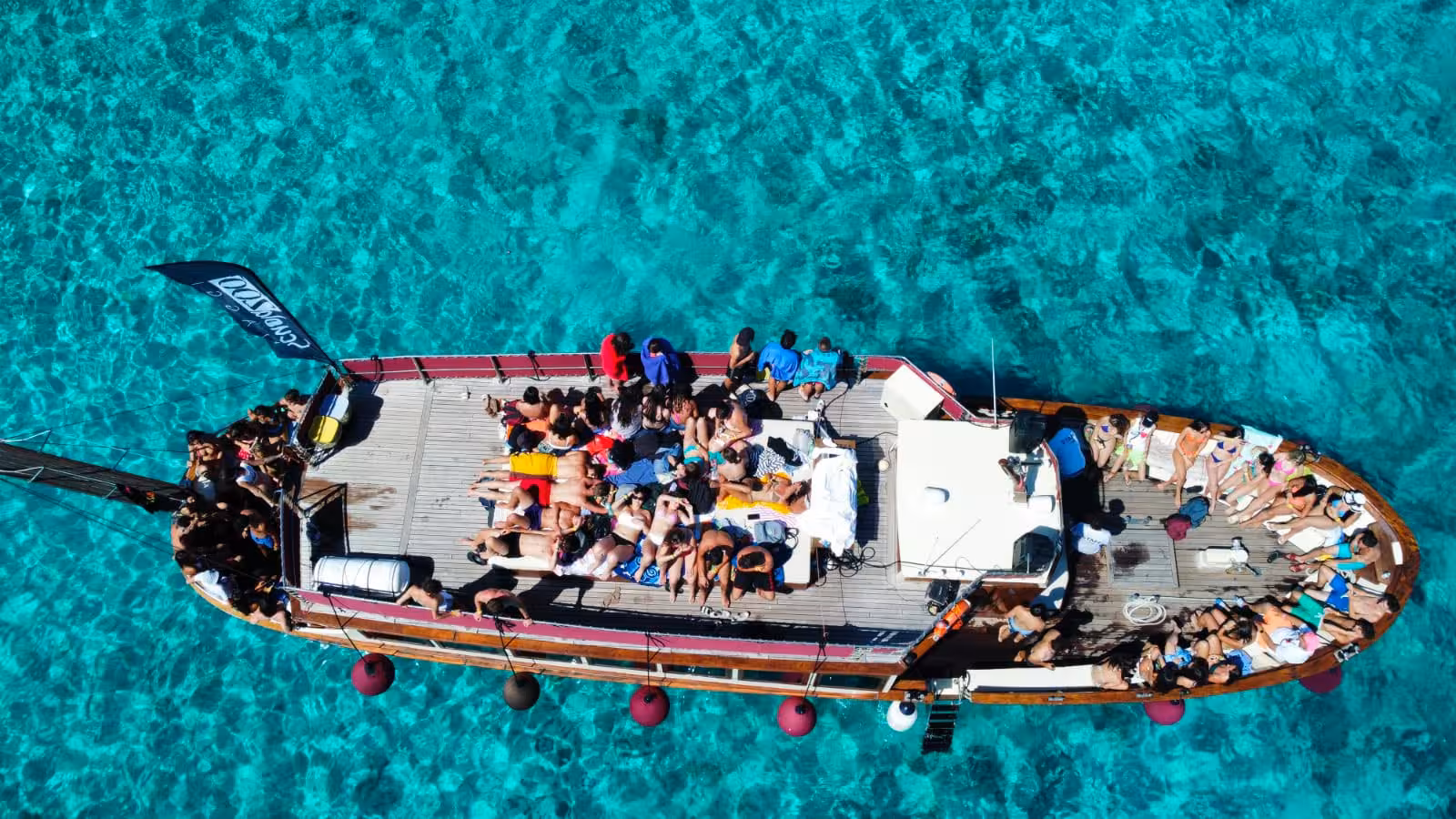 Aerial view of a motorboat with tourists relaxing on board in the crystal-clear waters of La Maddalena.