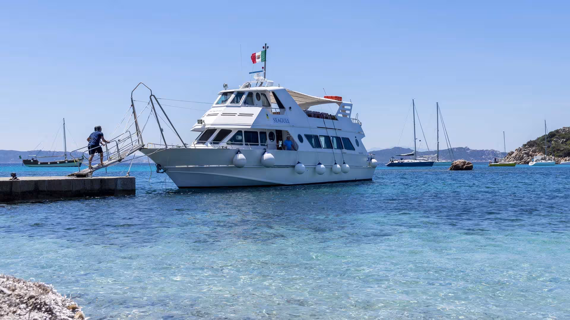 Passenger boarding a motorboat for a scenic tour of La Maddalena Archipelago from Santa Teresa di Gallura.