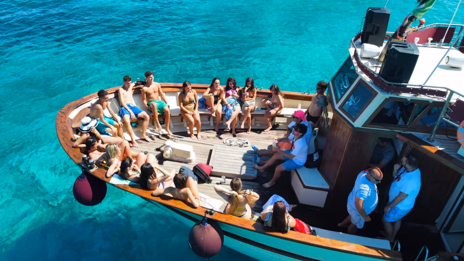 Tourists relax and enjoy the sun on a motorboat during the La Maddalena Archipelago tour, surrounded by crystal-clear waters.