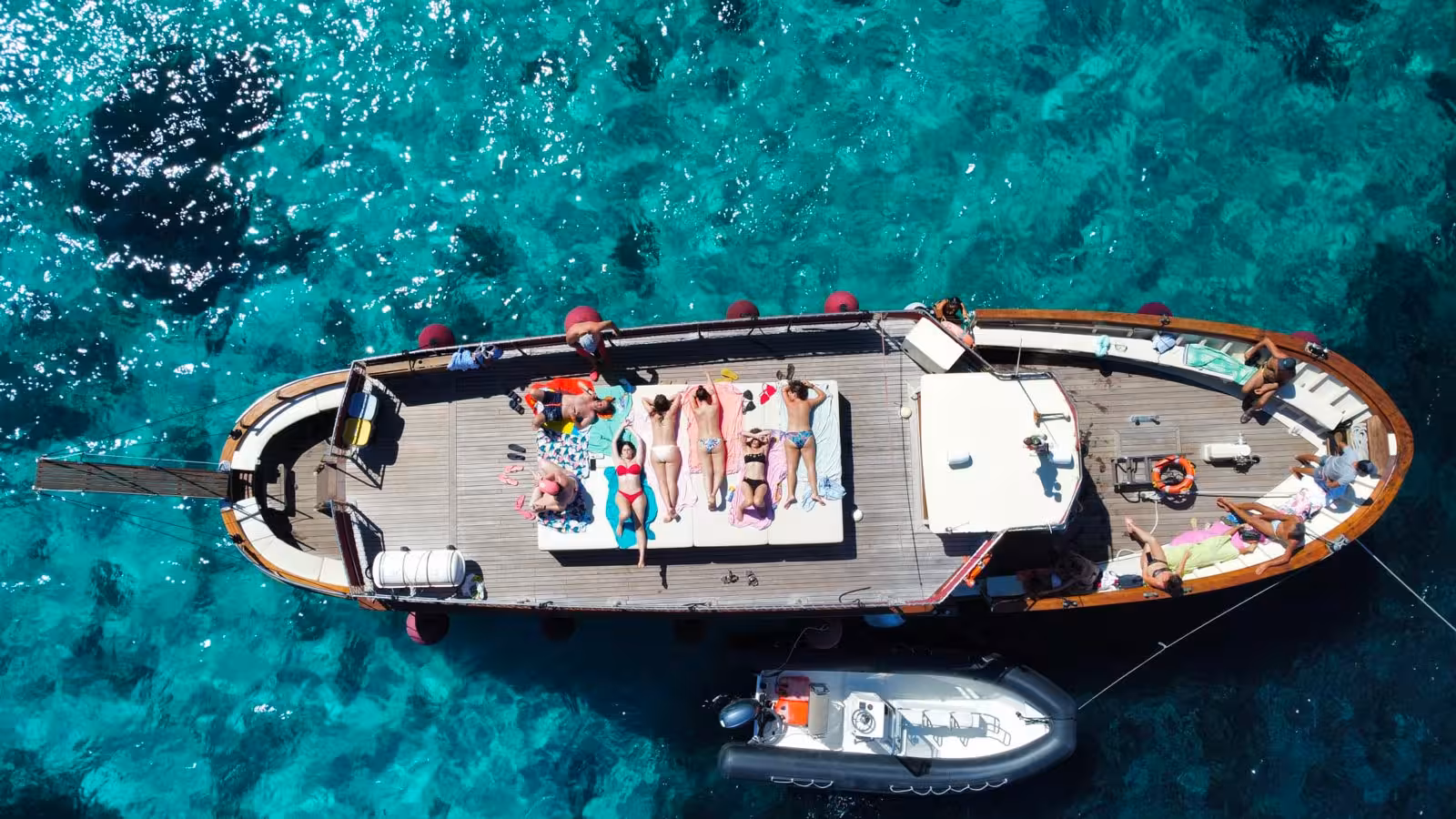 Tourists enjoy a scenic motorboat tour of the La Maddalena Archipelago under a clear blue sky.