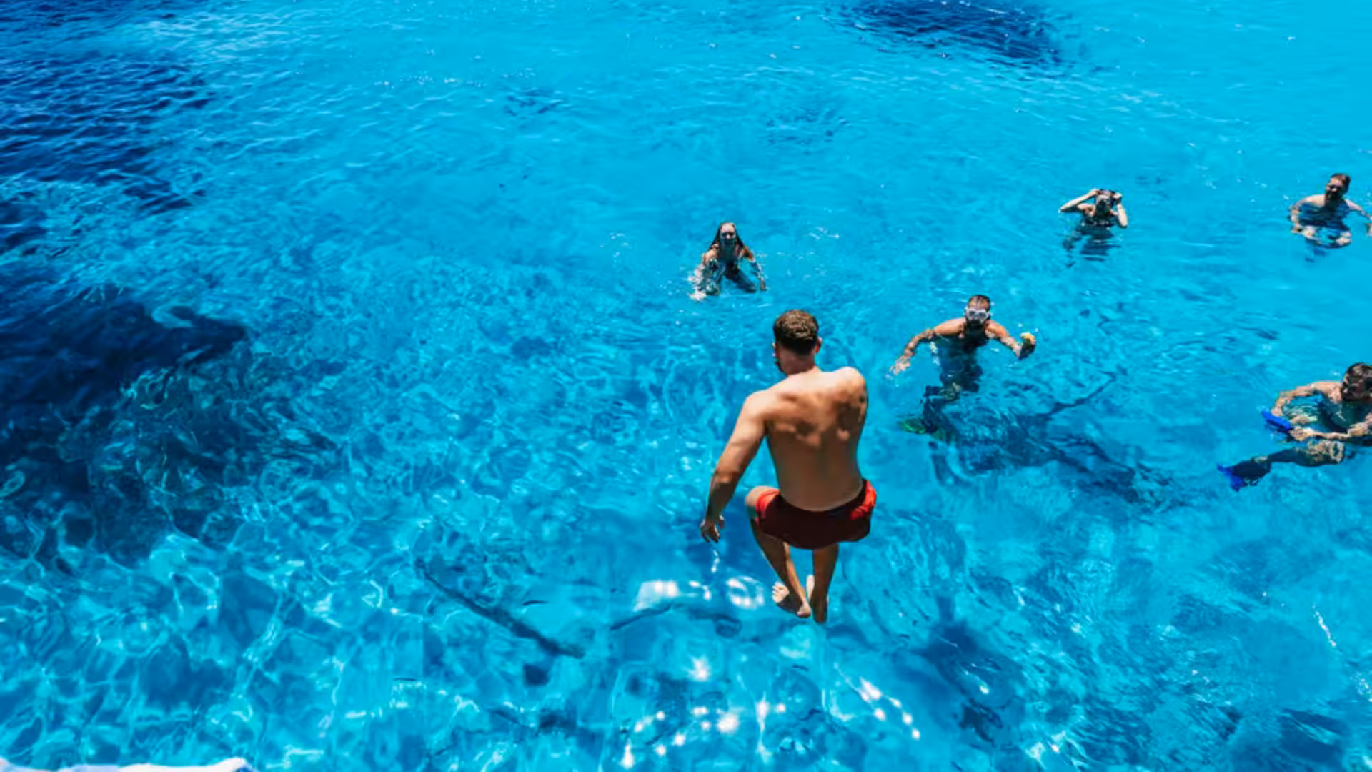 Tourists enjoy swimming in the crystal-clear waters of the La Maddalena Archipelago during a motorboat tour.