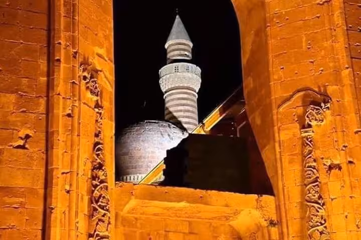 Historic mosque minaret framed by stone arch in eastern Turkey, cultural stop on Mount Ararat trek