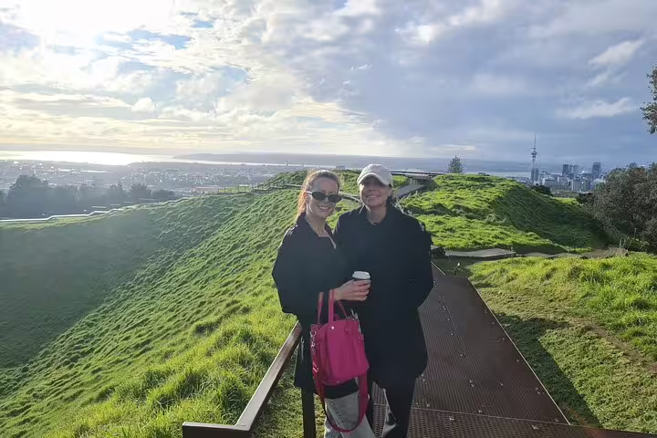 Visitors enjoying a scenic view from Mount Eden with Auckland skyline in the background during a private tour.
