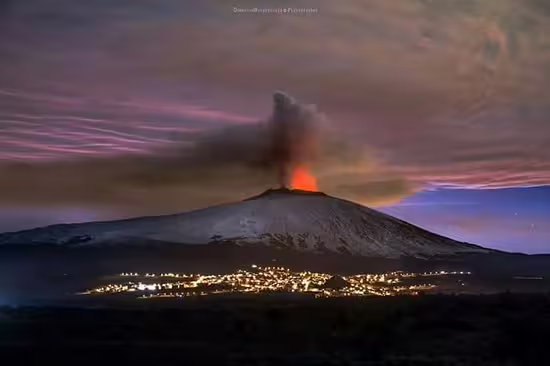 Night view of Mount Etna erupting above illuminated villages, a must-see on private excursions from Cefalù to Etna