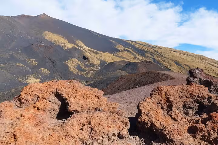 Stunning view of Mount Etna's volcanic landscape, showcasing rugged lava rocks and vibrant terrain under a clear sky.