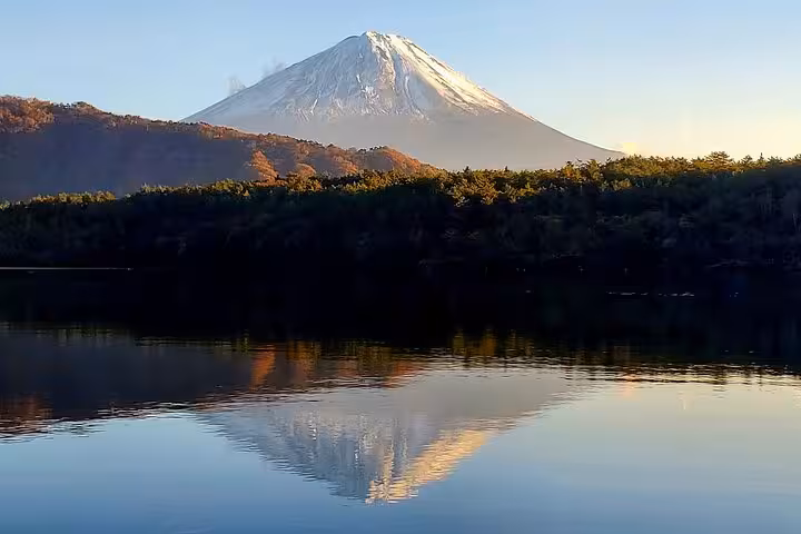 Majestic Mount Fuji reflecting on tranquil waters during a serene morning view in the Tokyo, Mt. Fuji, and Hakone tour.