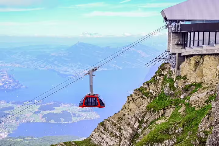 Red cable car ascending Mount Pilatus with panoramic views of Lake Lucerne and lush Swiss landscapes.